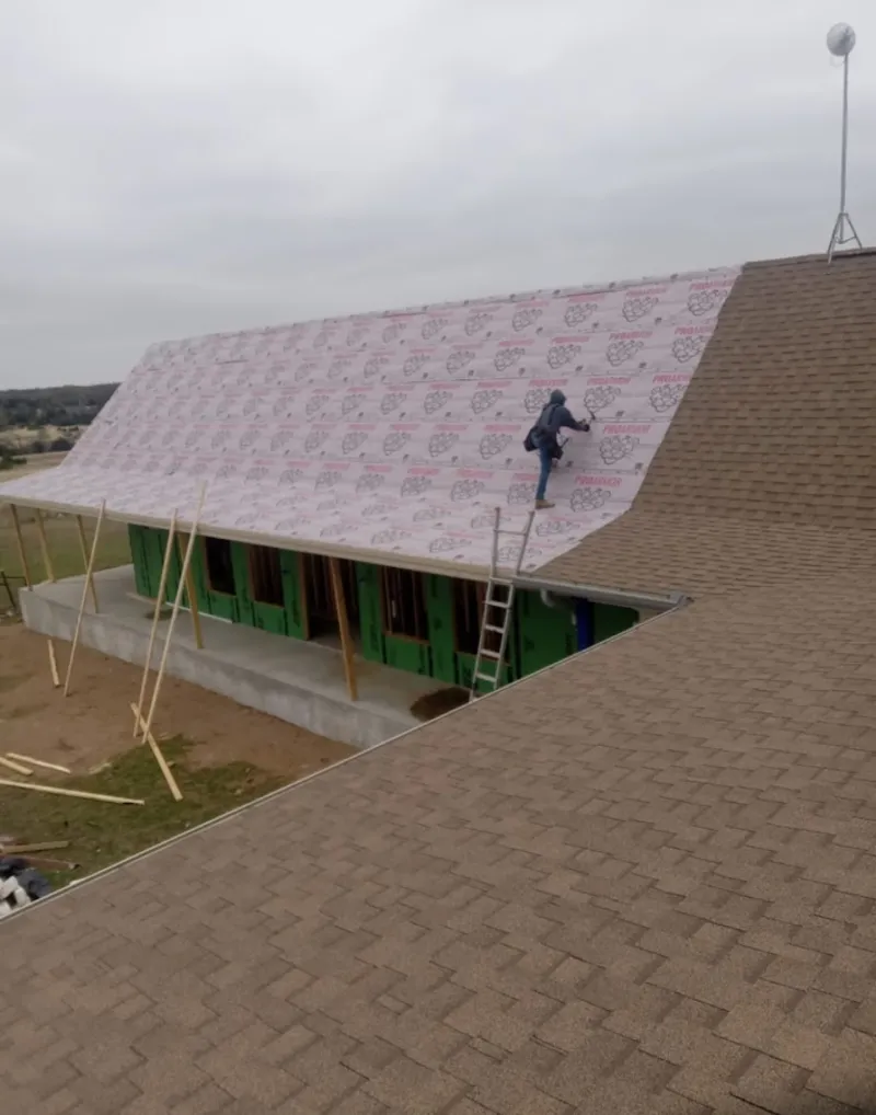 Worker preparing underlayment for a metal roof installation in Rome
